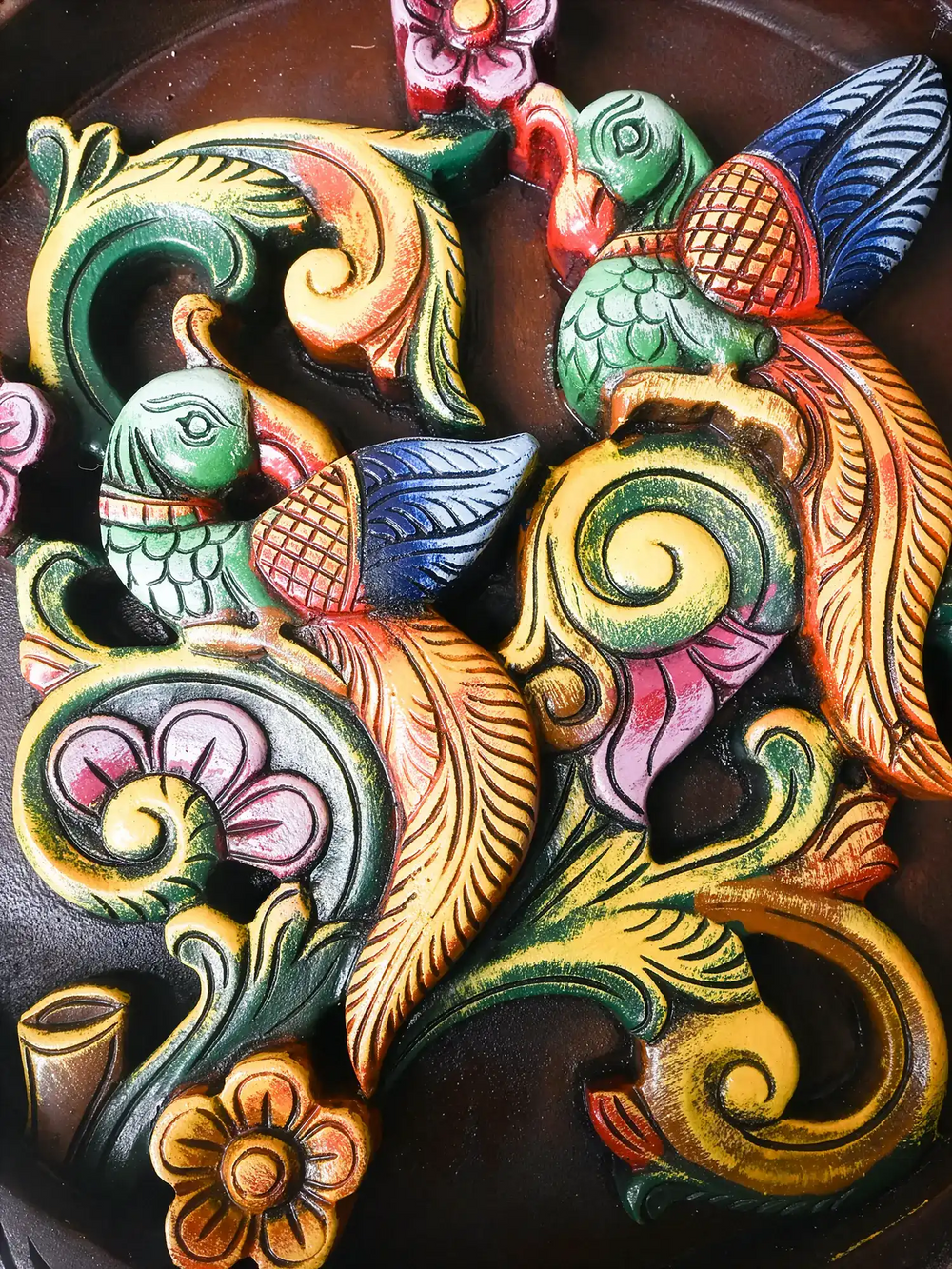 Colorful decorative relief with birds and floral elements on a dark background