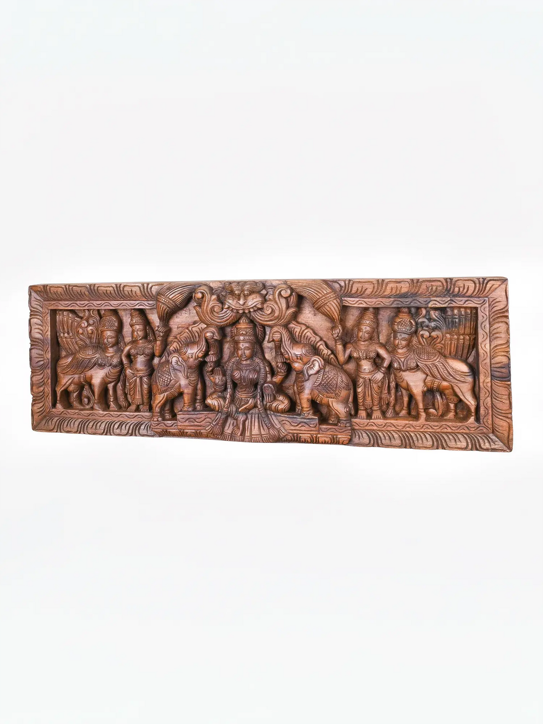 Elegant wooden Gajalakshmi carving with ornate temple border.