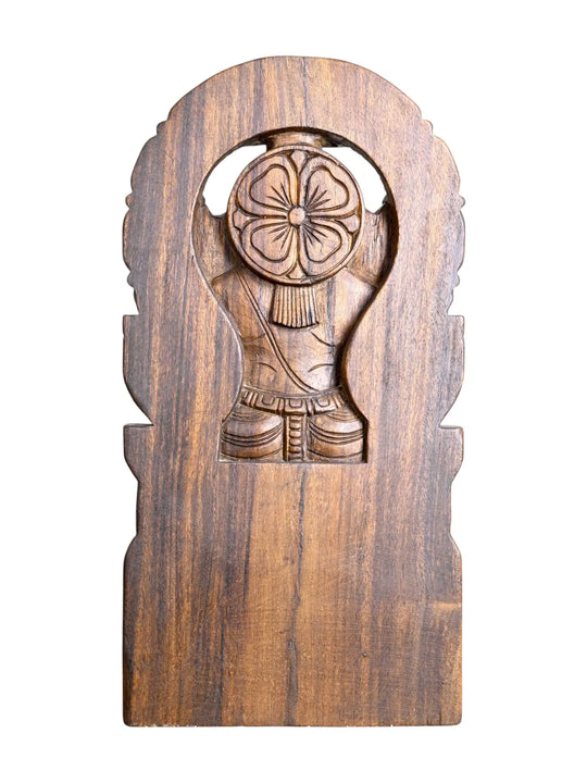 A hand-carved wooden wall plaque featuring a stylized figure holding a floral motif, set against a plain white background.