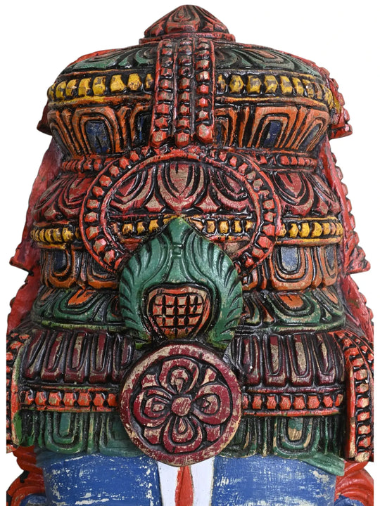 Macro shot of the intricately carved crown on a multicolored wooden Lord Vishnu wall mask.